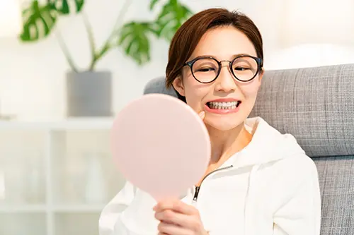 鏡で自分の歯並びを確認する女性